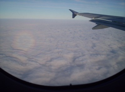 The glory, part of the plane wing, framed at bottom by the airplane window