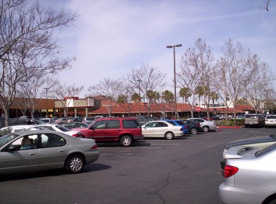 Panned right further, building continues in background with parked cars in foreground